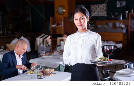 portrait of happy female garson standing in cafe 110483228