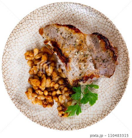 Fried piece of pork tenderloin garnish with stewed red beans decorated with parsley, spinach, basil leaves 110483315