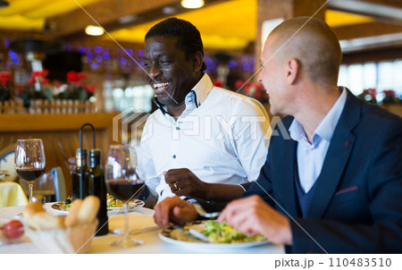 Friends enjoying dinner with wine at restaurant 110483510
