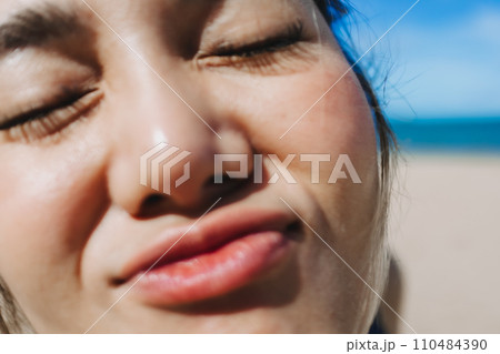 Close up face of happy woman in bright sunny beach in concept of skincare. 110484390