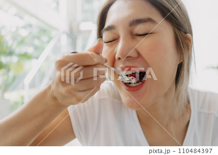 Funny face of happy woman eating cake carelessly in the cafe. 110484397