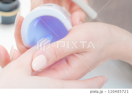ネイルサロン_ハンディライト（LED）でジェルを固めている2 110485721