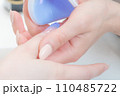 ネイルサロン_ハンディライト（LED）でジェルを固めている 110485722