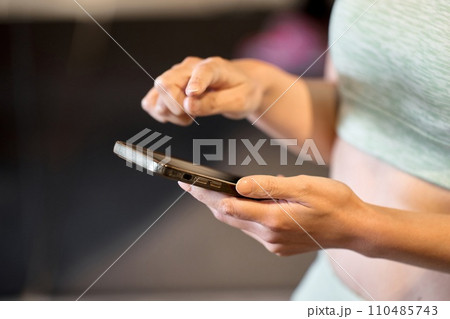 ジムでスマホアプリで管理をする女性 110485743