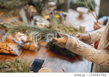 Actively involved in a workshop, a young lady creates handmade Christmas ornaments. 110485768