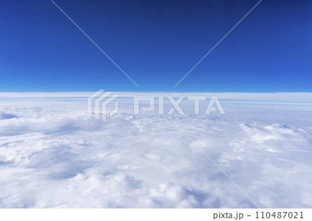 飛行機の窓から見た青空と雲海 110487021