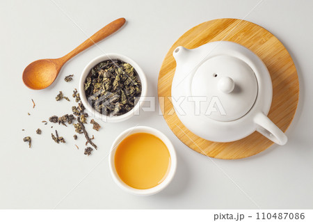 Cup of tea with dried tea leave, wood spoon and teapot on beige background, top view Cup of tea with dried tea leave, wood spoon and teapot on beige background, top view 110487086