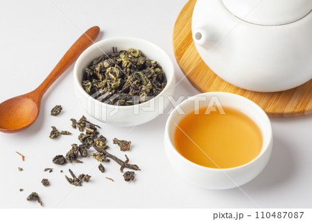 Cup of tea and dried tea leave with teapot and spoon on white table, closeup Cup of tea and dried tea leave with teapot and spoon on white table, closeup 110487087