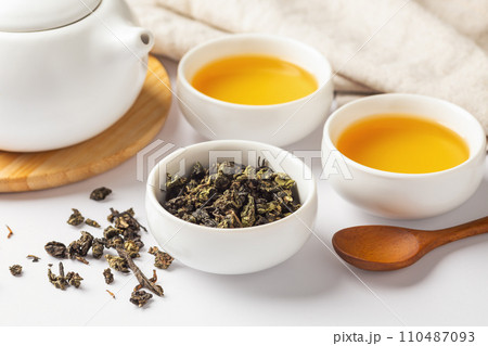 Tea leave in cup, closeup with tea set on white table Tea leave in cup, closeup with tea set on white table 110487093