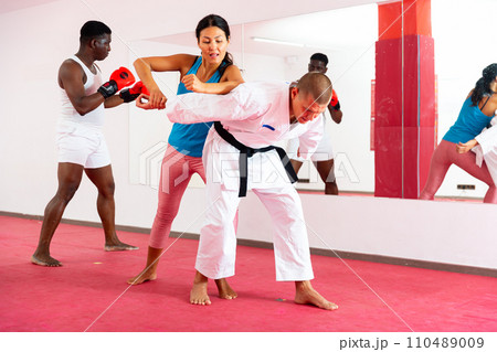 Asian woman is training with man on the self-defense course in sport gym Asian woman is training with man on the self-defense course in sport gym 110489009