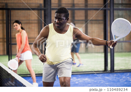 Sporty african american playing padel on indoor court 110489234