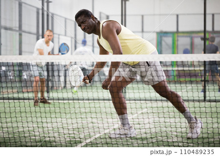 African american paddle tennis player preparing to hit ball on court 110489235