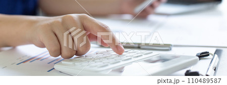 Accounting businessmen are calculating income-expenditure and analyzing real estate investment data, She works on a desk has graphs and calculators with laptop, Financial and tax systems concept. Accounting businessmen are calculating income-expenditure and analyzing real estate investment data, She works on a desk has graphs and calculators with laptop, Financial and tax systems concept. 110489587