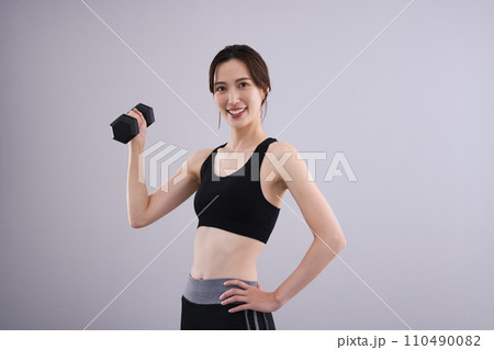 スポーツウエアでダンベルを持つ女性 110490082