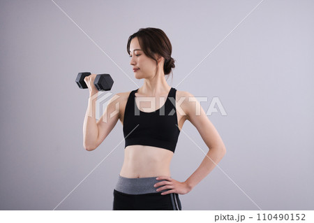 スポーツウエアでダンベルを持つ女性 110490152