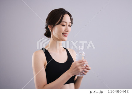 スポーツウェアで水分補給する女性 110490448