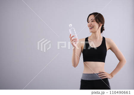 スポーツウェアで水分補給する女性 110490661