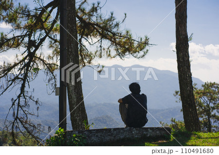 landscape and travel concept with solo freelancer man sit on wooden and use tablet work from outdoor with layer of mountain background 110491680