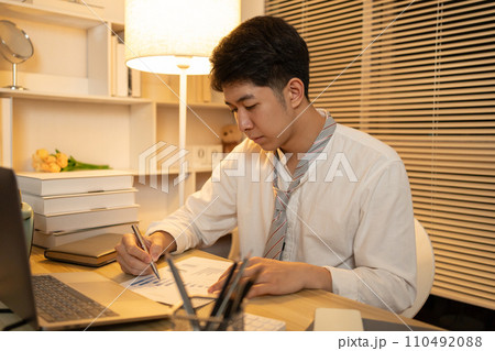 Businessman analyzes data graphs and works intently in his personal office, Working in the middle of the night. Businessman analyzes data graphs and works intently in his personal office, Working in the middle of the night. 110492088