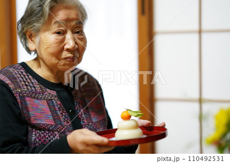 仏壇にお供え餅を供える高齢女性 110492531