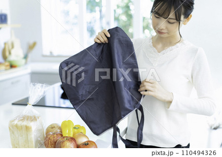 キッチンでエコバックを持って困り顔の若い女性 110494326