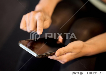 ジムでスマホアプリで管理をする女性 110494349