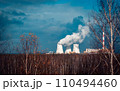 Nuclear power plant cooling towers concept photo. Big chimneys. Forest with partly cloudy sky in Polish province. 110494460