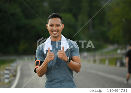Smiling muscular man showing thumbs up for symbol good health. Sport and healthy life concept 110494781