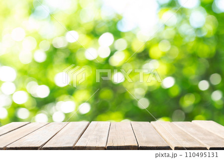 Empty wooden table and blurred green background Empty wooden table and blurred green background 110495131