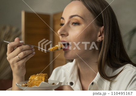 Close-up of a woman eating a honey cake Close-up of a woman eating a honey cake 110495167