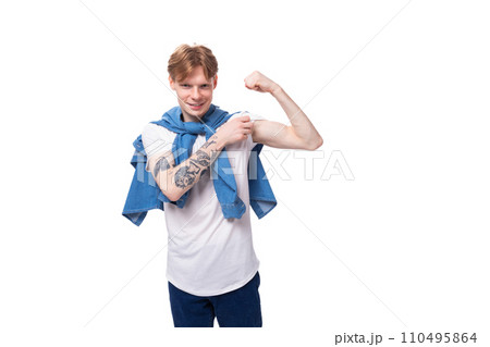 young well-groomed slender red-haired man in a stylish blue shirt on a white background with copy 110495864