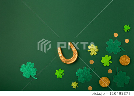 Golden Horseshoe, Gold Coins and Clover Leaves Shamrocks on Green Background for St Patricks Day Concept. 110495872