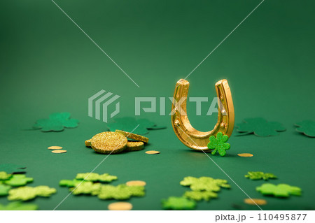Golden Horseshoe, Gold Coins and Clover Leaves Shamrocks on Green Background for St Patricks Day Concept. 110495877