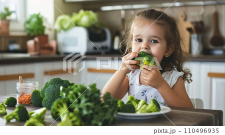 happy child eats broccoli in modern kitchen. portrait 110496935