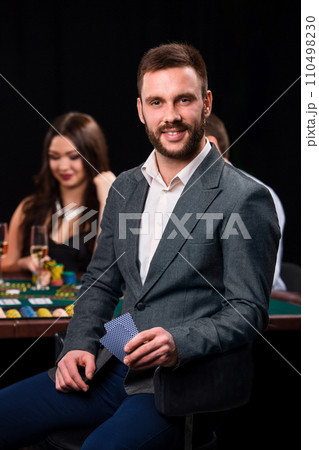 Poker players in casino with cards and chips on black background 110498230
