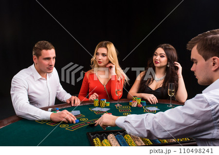Friends enjoying a gambling night. The dealer deals the cards Friends enjoying a gambling night. The dealer deals the cards 110498241