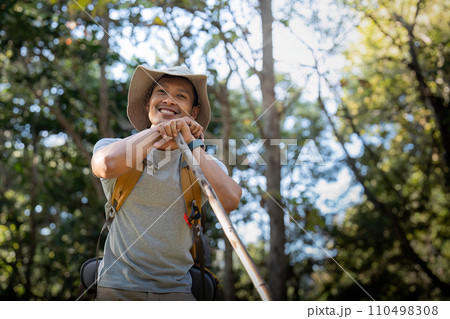 Young man asian trekking among trees with backpack, young man enjoy alone in forest. Camping, hiking, travelling, search for adventure concept Young man asian trekking among trees with backpack, young man enjoy alone in forest. Camping, hiking, travelling, search for adventure concept 110498308