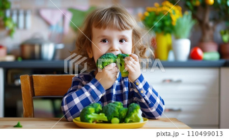 happy child eats broccoli in modern kitchen. portrait 110499013