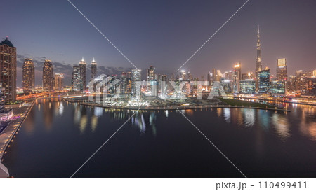 Aerial panorama of Dubai Business Bay and Downtown with the various skyscrapers and towers day to night timelapse 110499411
