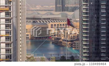 Aerial view of Dubai Fountain in downtown with palms in park next to shopping mall and souq timelapse, UAE Aerial view of Dubai Fountain in downtown with palms in park next to shopping mall and souq timelapse, UAE 110499464