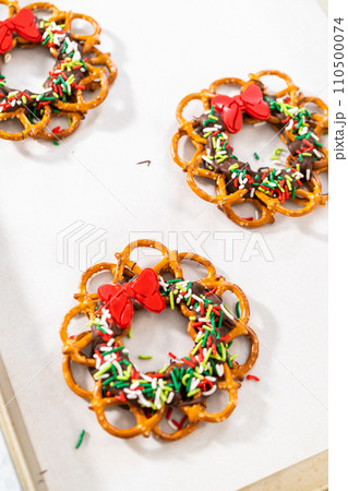 Dipping pretzels twists into melted chocolate to make a chocolate pretzel Christmas wreath. Dipping pretzels twists into melted chocolate to make a chocolate pretzel Christmas wreath. 110500074