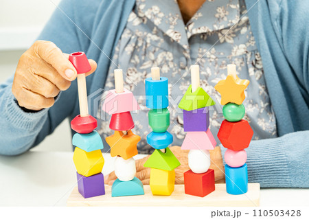 Alzheimer disease AD, Asian elderly woman patient suffering from dementia learn practical motor skills rehabilitation. Alzheimer disease AD, Asian elderly woman patient suffering from dementia learn practical motor skills rehabilitation. 110503428