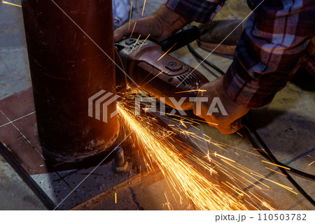 While grinding iron worker cuts metal with an abrasive disk sparks 110503782