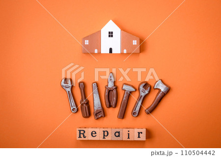 Repair or home improvement tools and a house model on a plain background Repair or home improvement tools and a house model on a plain background 110504442