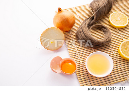 Hairloss concept. Onions, lemon, egg and hair isolated on a wooden background Hairloss concept. Onions, lemon, egg and hair isolated on a wooden background 110504852