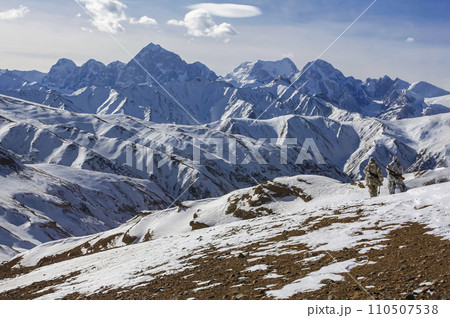 Hunters in winter camouflage inspect the mountain slopes in search of animals. 110507538