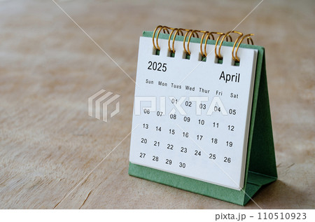 April 2025 table calendar on wooden desk with customizable space for text. Copy space and calendar concept 110510923