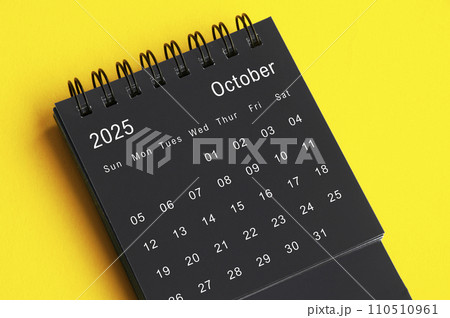 October 2025 black and white desk calendar on yellow cover background. Calendar concept 110510961