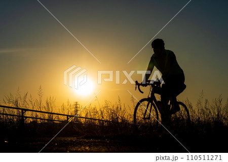 夕日とロードバイクに乗る人のシルエット 夕日とロードバイクに乗る人のシルエット 110511271