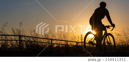 夕日とロードバイクに乗る人のシルエット 110511351